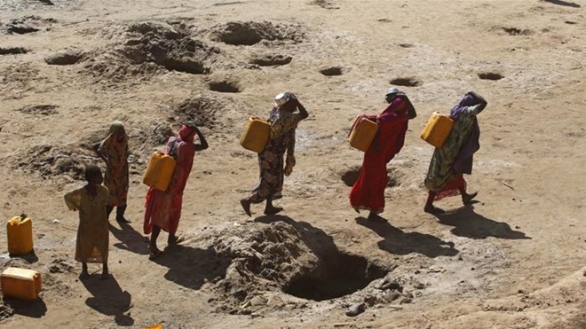 Women carry jerry cans of water from shallow wells dug from the sand along the Shabelle River bed in Somalia's Shabelle region, March 19, 2016 [Feisal Omar/Reuters]